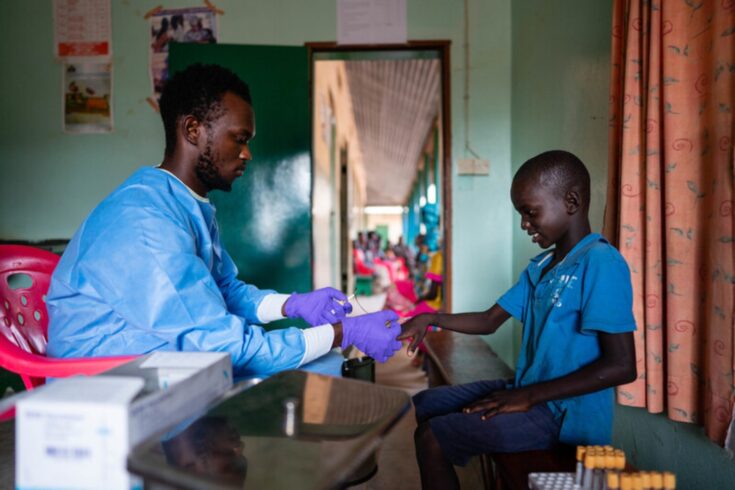 Clinician takes a blood sample from a young boy