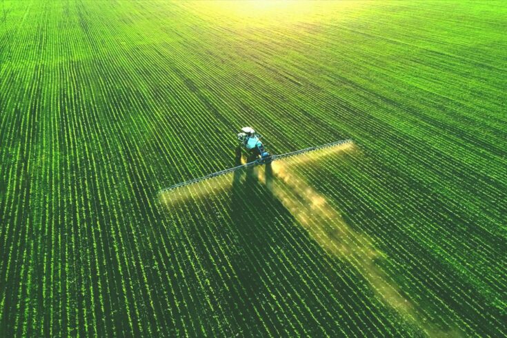Tractor spraying fertiliser on green field