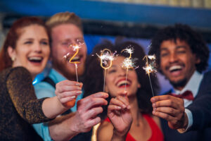 Joyful young people holding sparklers in a club.