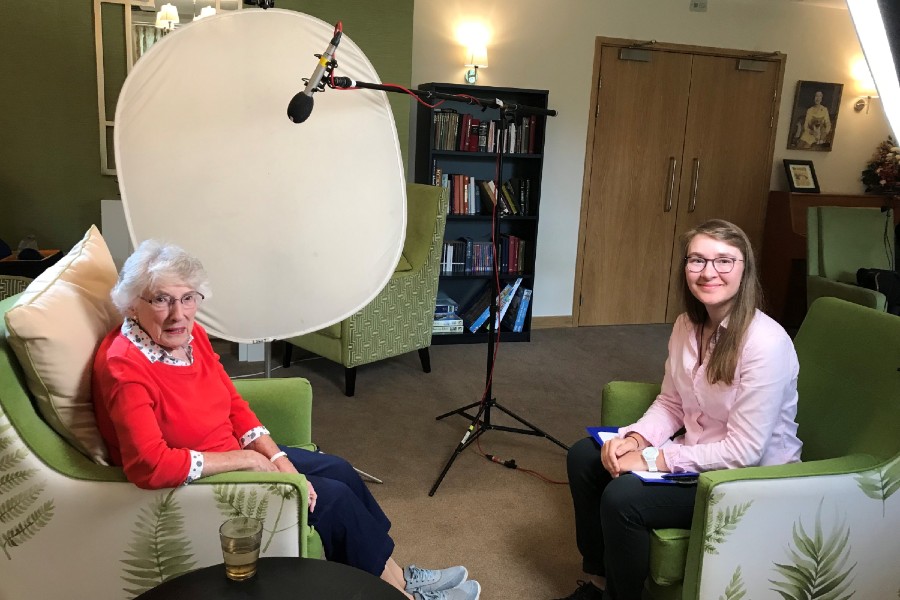 A younger woman sits opposite a senior woman ready for an interview