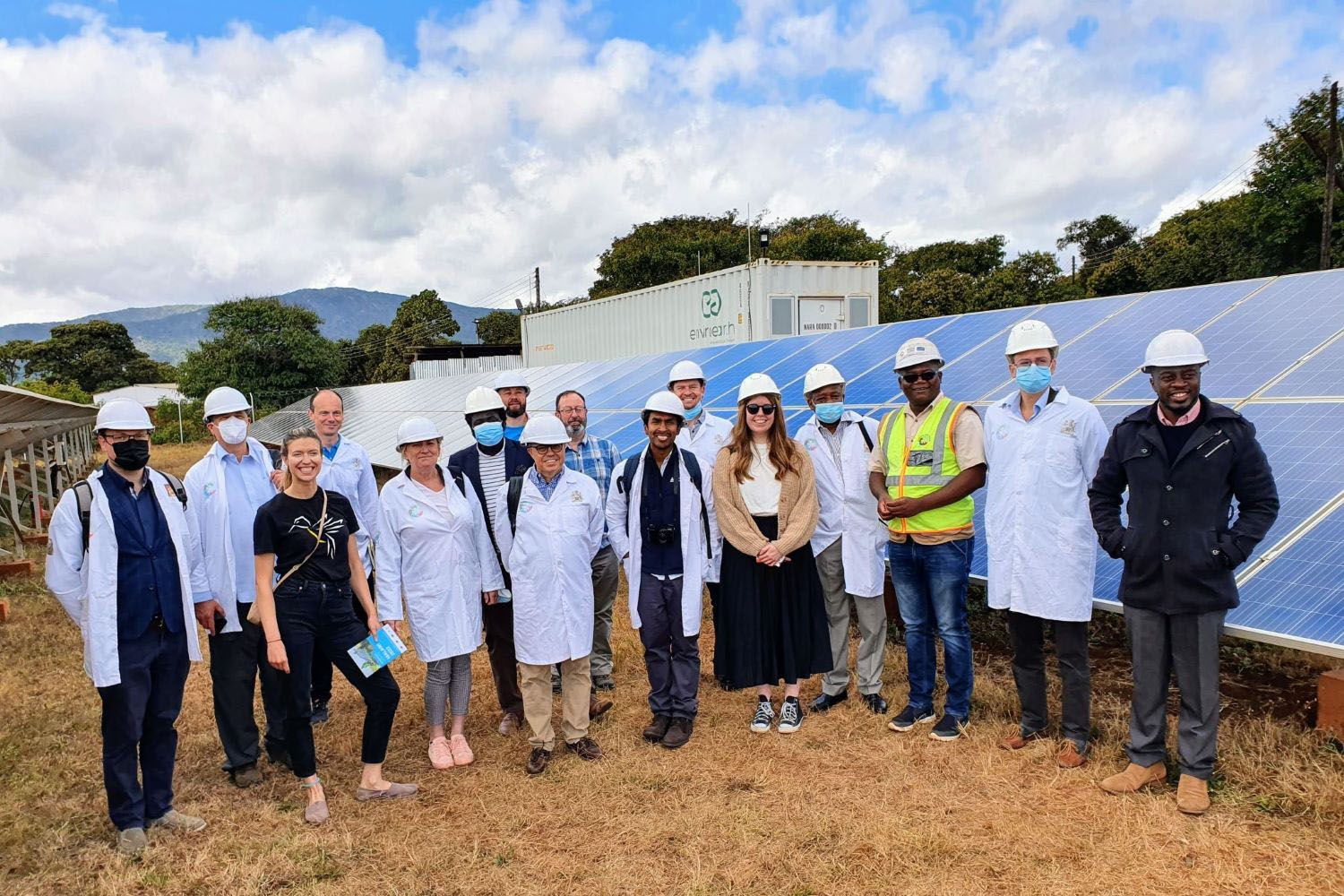 Energy Catalyst cohort standing in front of a solar mini grid. 