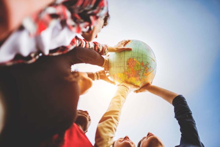 Teenagers holding a globe ball together