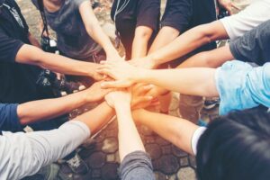 Group of people stood in a circle with their hands together in the middle