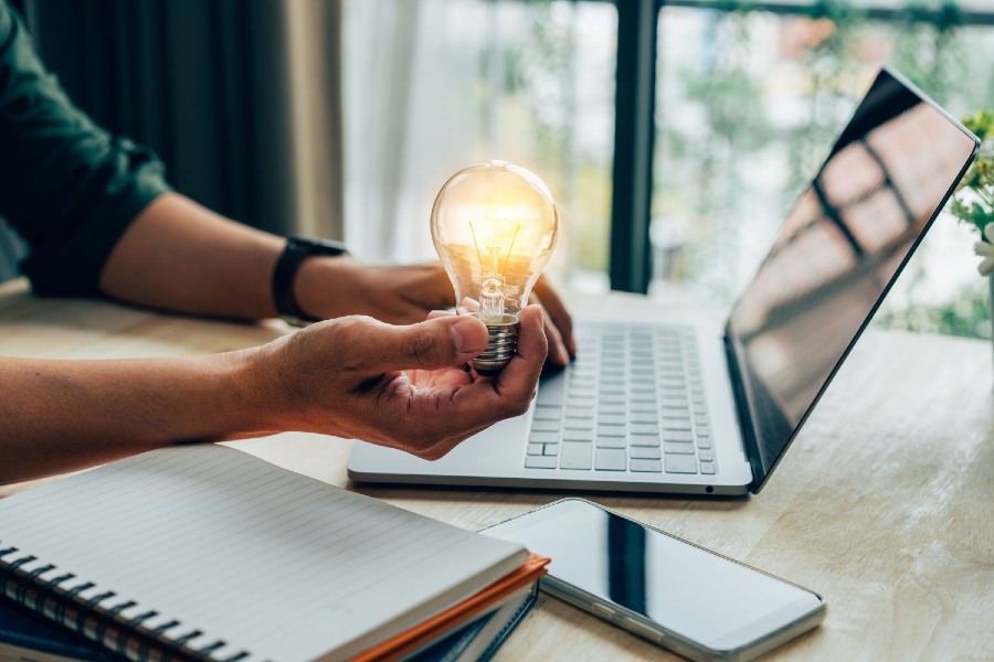 Hand holding a bright lit lightbulb