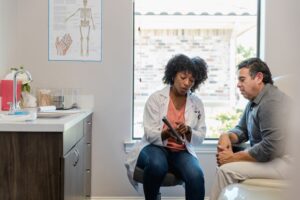 A doctor points out something on the digital tablet as patient listens carefully.