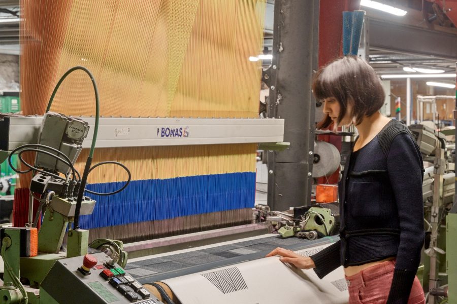 Woman stood next to a weaving machine