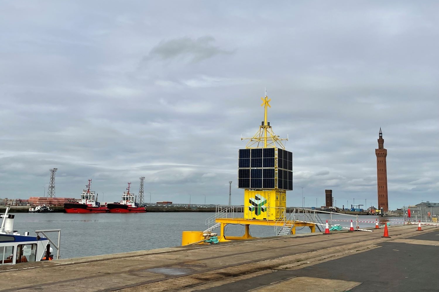 Boat dock with a small square yellow structure out over the water with solar panels on all sides. 