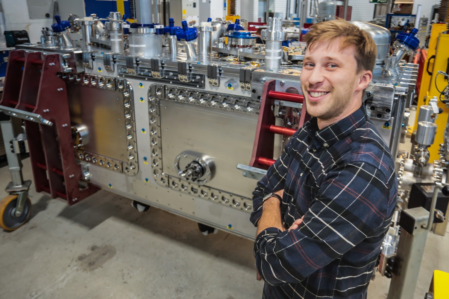 Smiling man stood in front of large steel piece of lab equipment