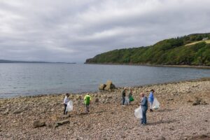 A group of people clearing up litter on a beach.