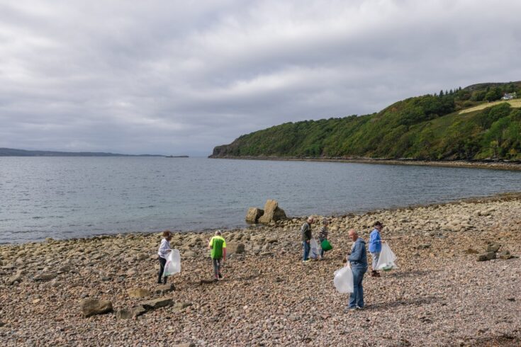 A group of people clearing up litter on a beach.