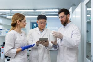 A team of three scientists standing inside a laboratory, discussing a scientific project