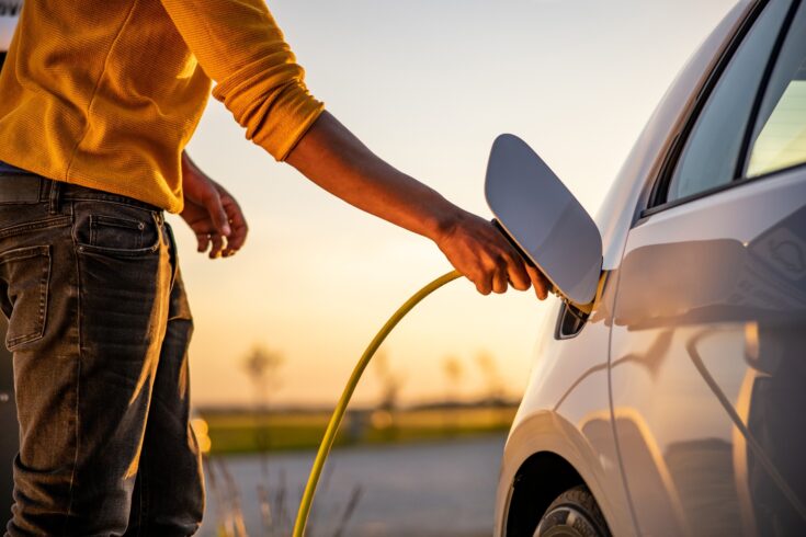 Man inserting plug into an electric car charging socket.