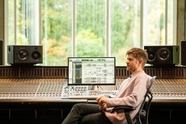 Oli Jacobs sitting at a sound desk with a screen.