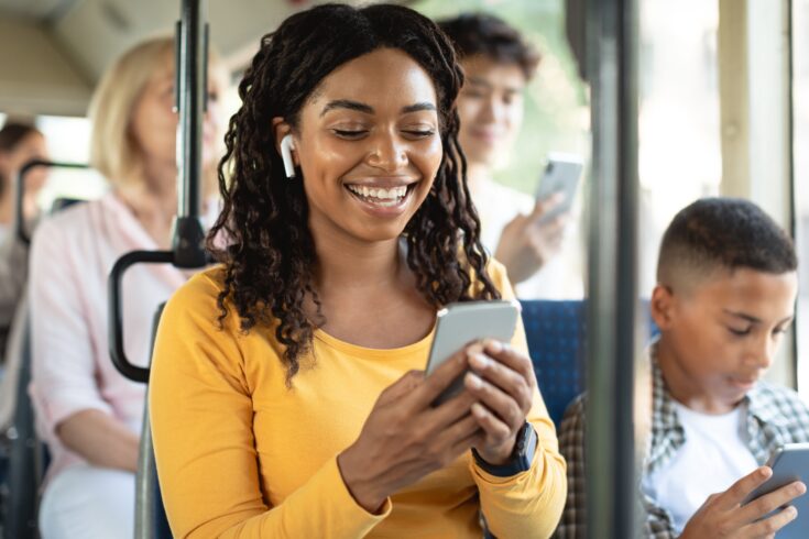 Smiling woman using her smartphone on the bus.