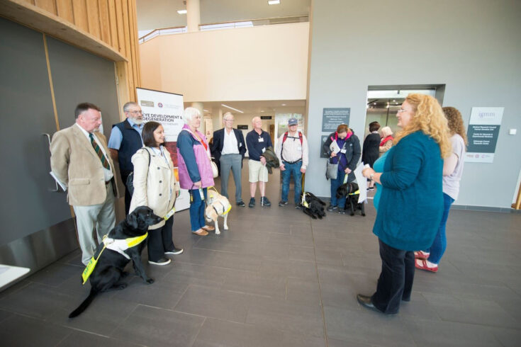 Patient delegates and service animals gather to tour scientific facilities at a 2017 eye development and degeneration conference hosted by the MRC Human Genetics Unit.