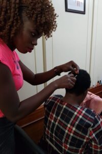 A community researcher collects a hair sample from the head of a study participant