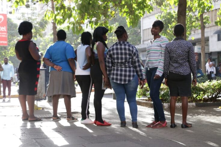 Maisha Fiti study champions standing in a line on a pavement, waiting for a taxi for field work