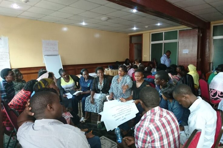 Maisha Fiti study team consulting with study champions, sitting down on chairs in a large circle