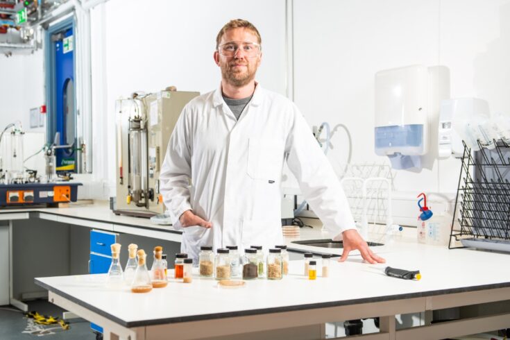 Professor Chris Chuck stands in his lab with samples of feedstock.