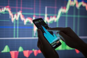 A businessman checking stock market data. He is using a mobile phone to analysis economy data on forex earn graph.