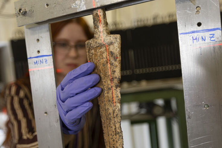 A female user in the ISIS Neutron and Muon Source facility touching an ancient sword.