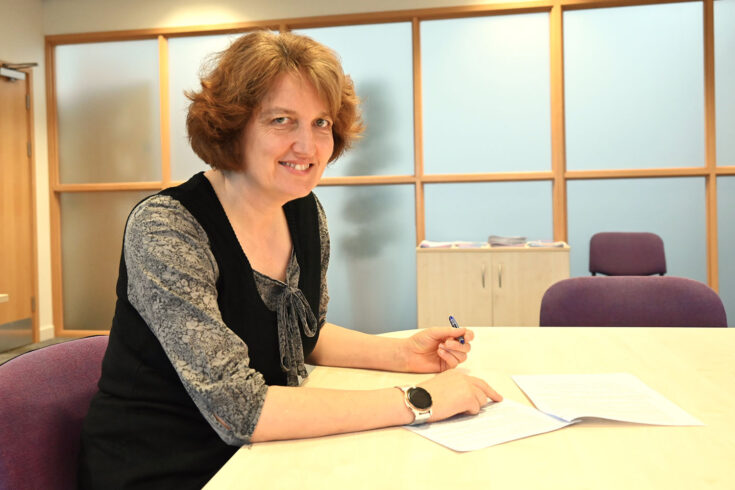 Hartree Centre Director Kate Royse sitting at a table signing the collaboration agreement with Coventry University for the Digital and AI Skills Network.