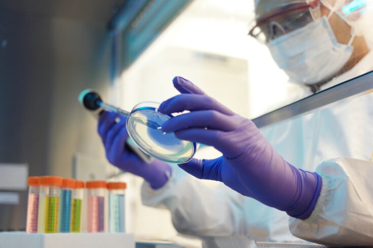 A scientist handling a petri dish in a cleanroom.