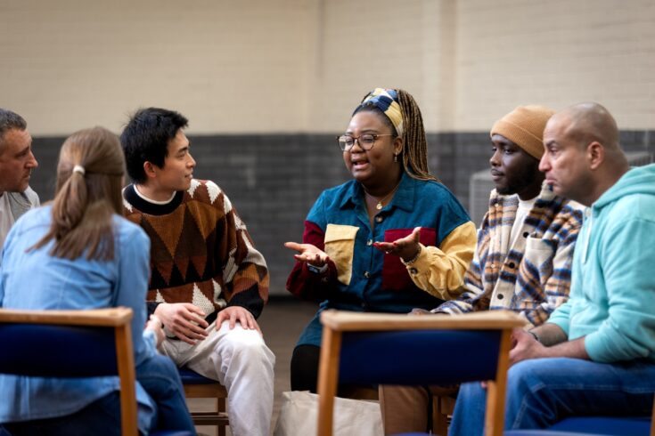 Members of a community group having a conversation while sitting in a circle on chairs.