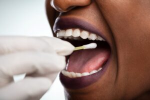 Taking a saliva test from a woman's mouth with cotton swab