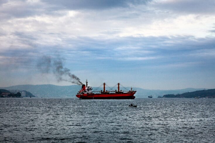 A ship on the sea, releasing emissions into the air.