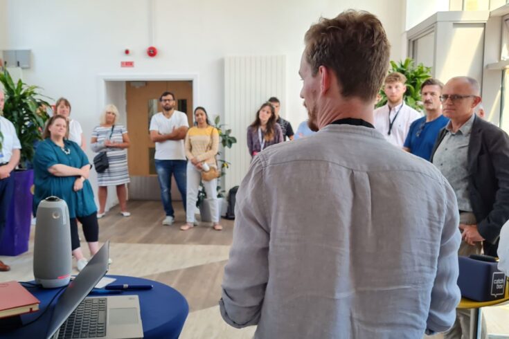 A group of people standing and listening to a person talk