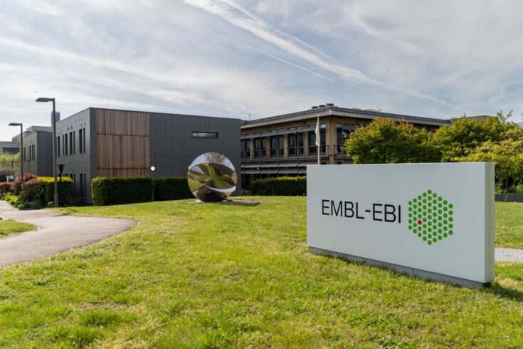 Several of the EMBL-EBI buildings are in the background with signage for the institute in the forefront.