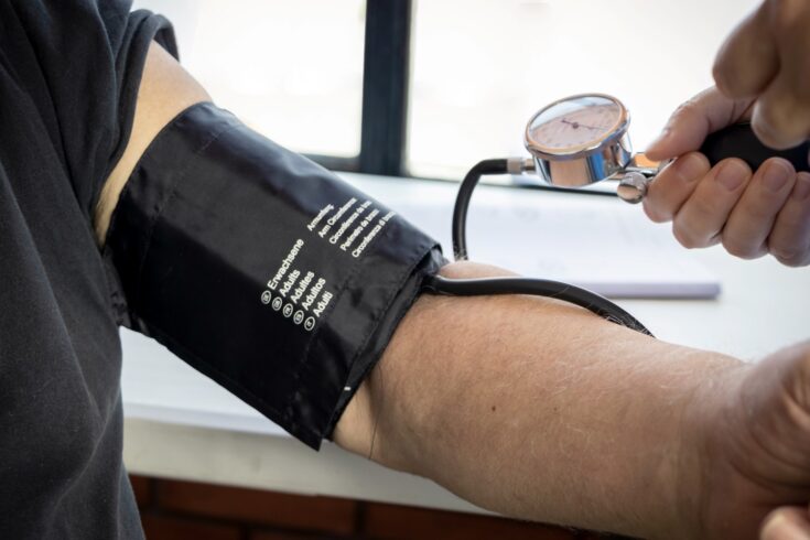 health worker in a blue uniform taking the blood pressure of an elderly person with a sphygmomanometer