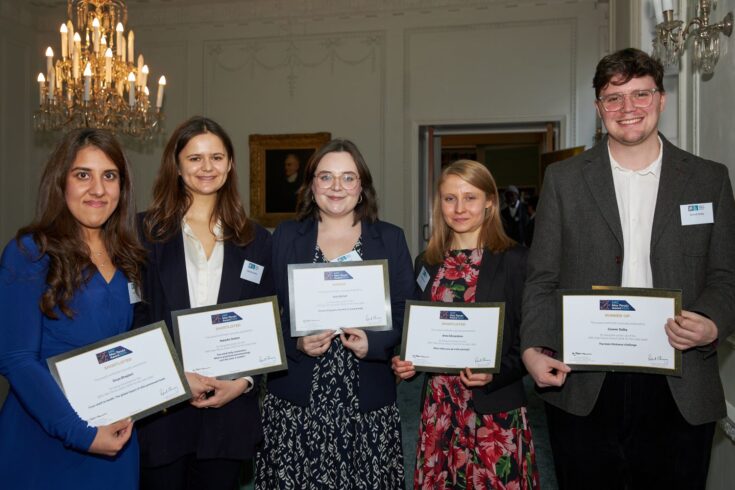 Four women and a man holding their certificates and smiling