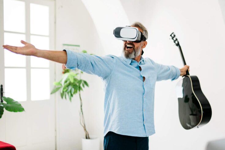 Man wearing a VR headset and holding guitar