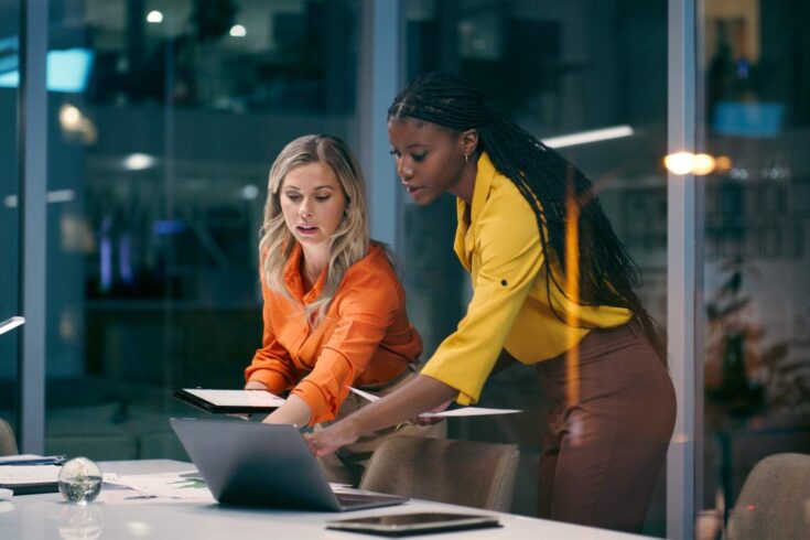 Two women working together with laptop and tablet in office