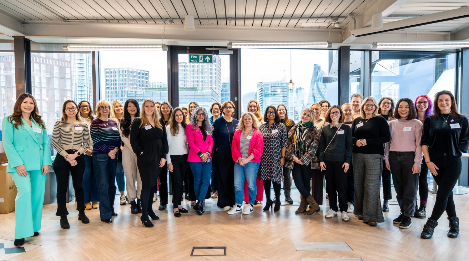 A group of women standing in a row in a large room.