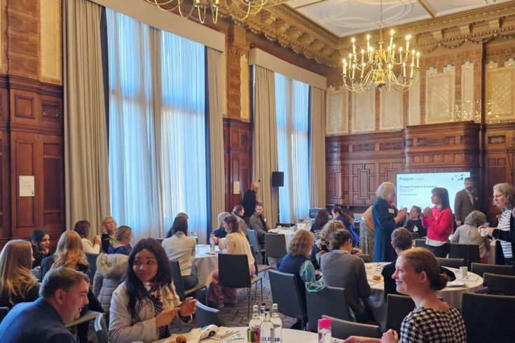 Men and women sat down at round tables in a formal room.